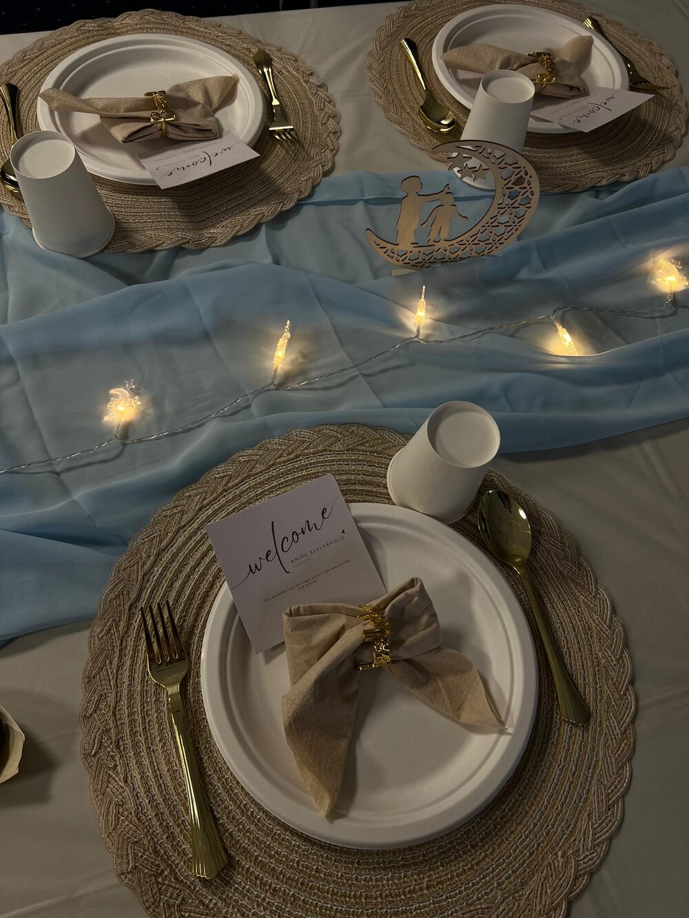 Gedekte iftartafel met welkomstkaartjes, gouden bestek en lichtjes