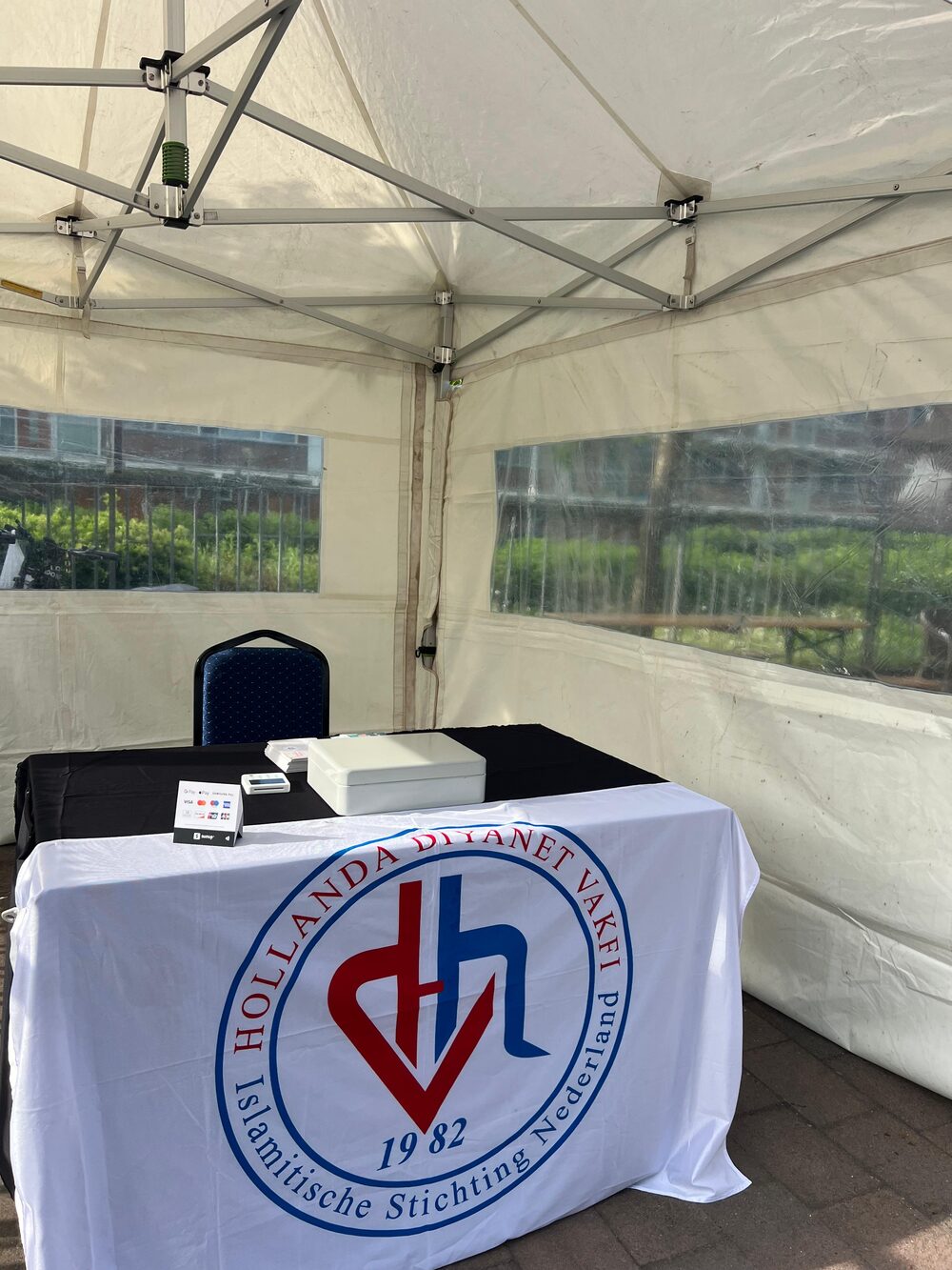 De informatiestand met het tafelkleed van de Hollanda Diyanet Vakfı in een witte tent